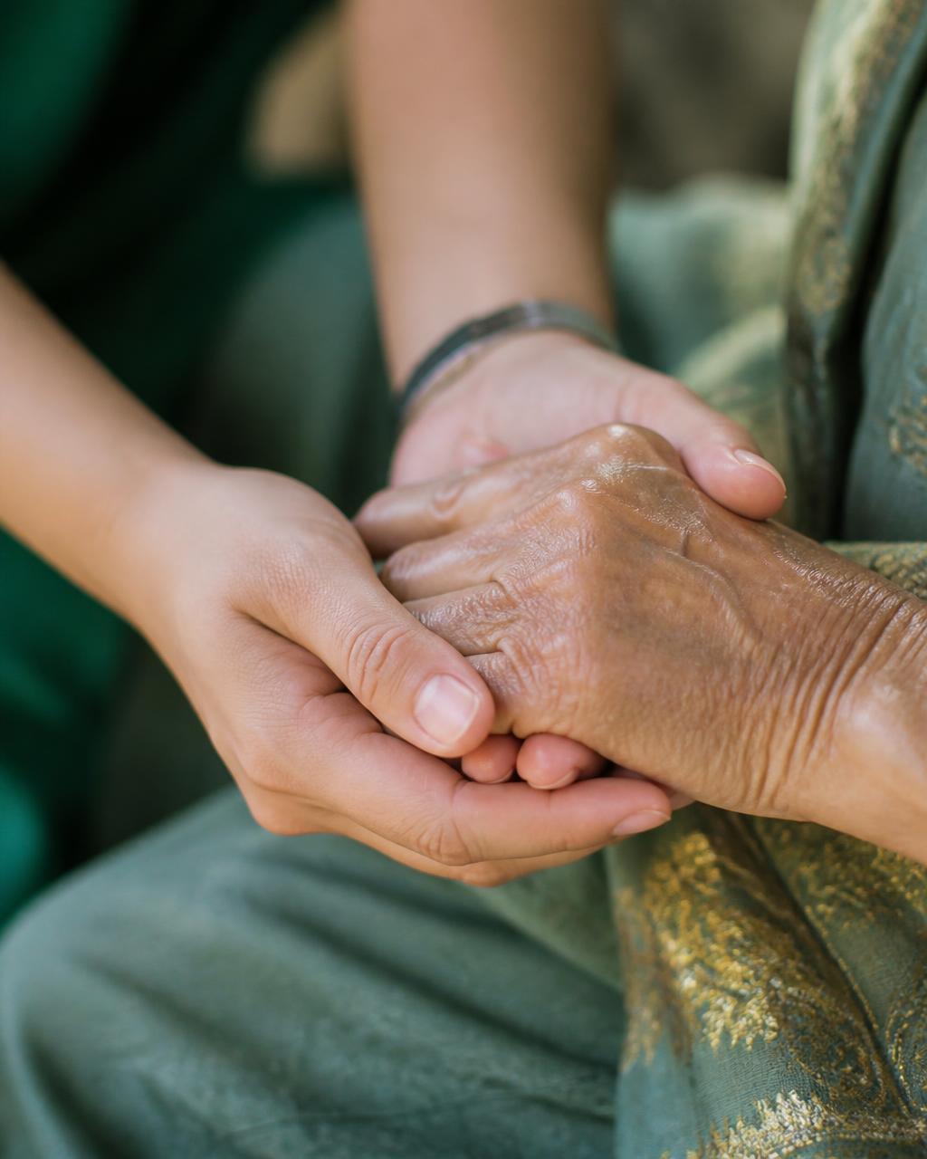 A caregiver gently holding an elderly resident's hands